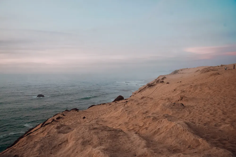 Quiet coastline in Tamraght Morocco with soft Atlantic waves and empty sandy cliffs at sunset