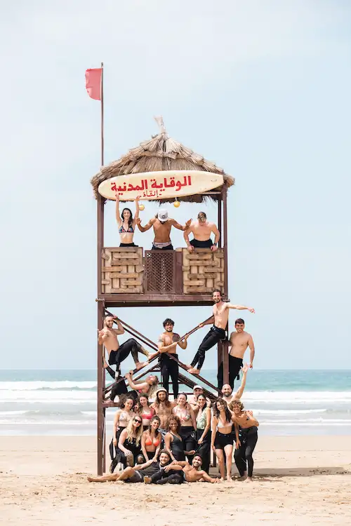 Group of surfers smiling together on the beach in Tamraght after a surf session