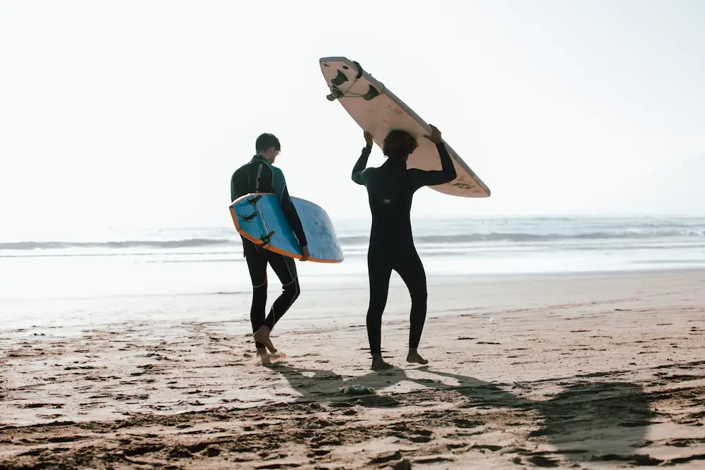 Surfer walking alone toward the ocean in Tamraght Morocco carrying a surfboard